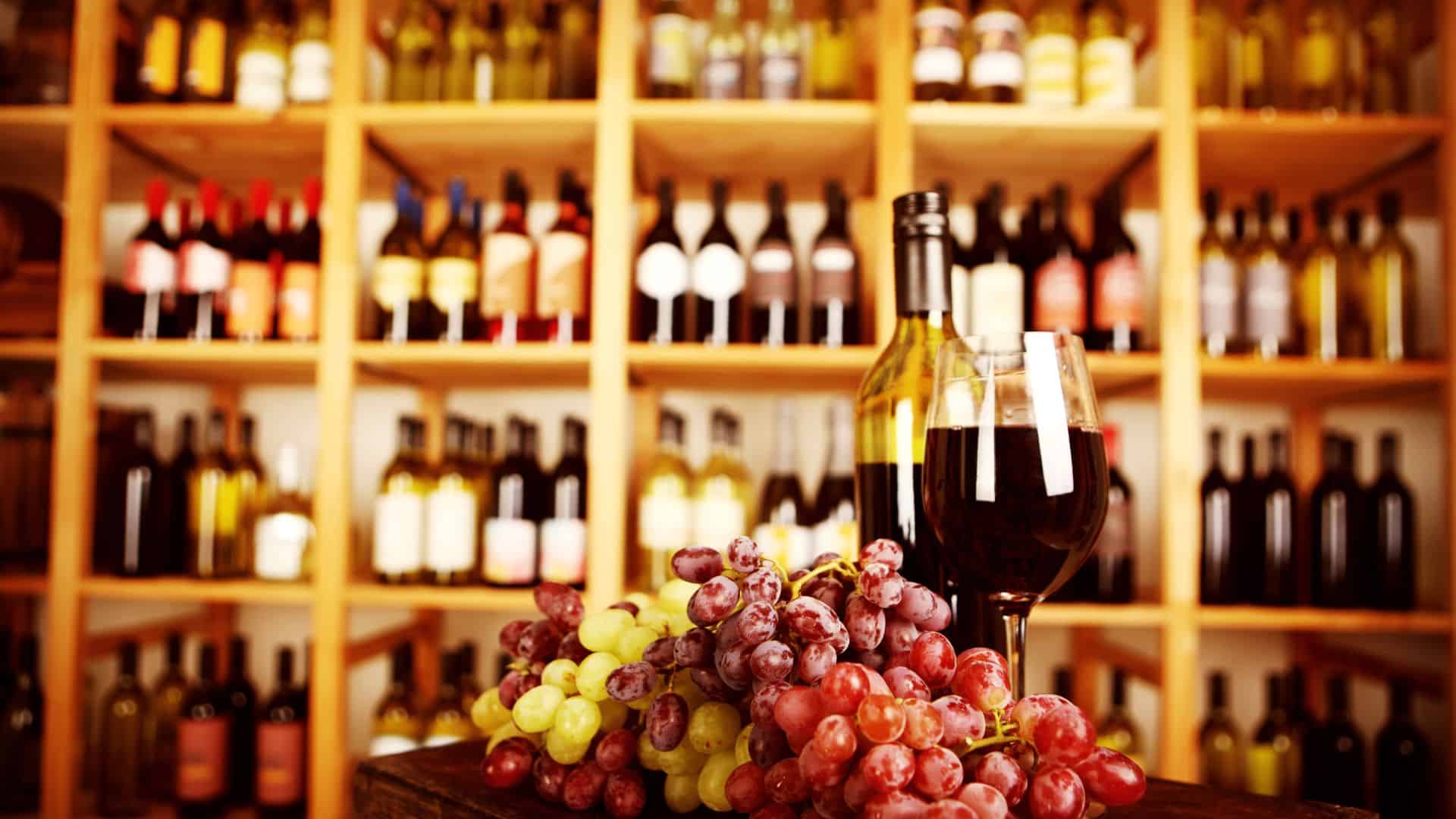 a wall of wine bottles with one glass poured