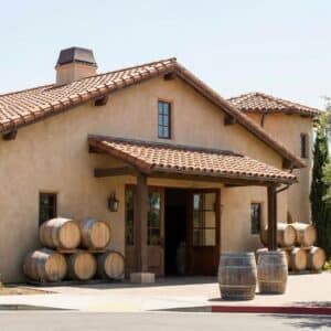 Exterior of a classic Edna Valley winery building with terracotta roof and wine barrels.